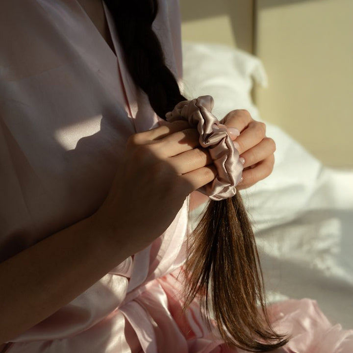 Jadu Mulberry Silk Scrunchie being put into hair before bed for all night protection against breakage